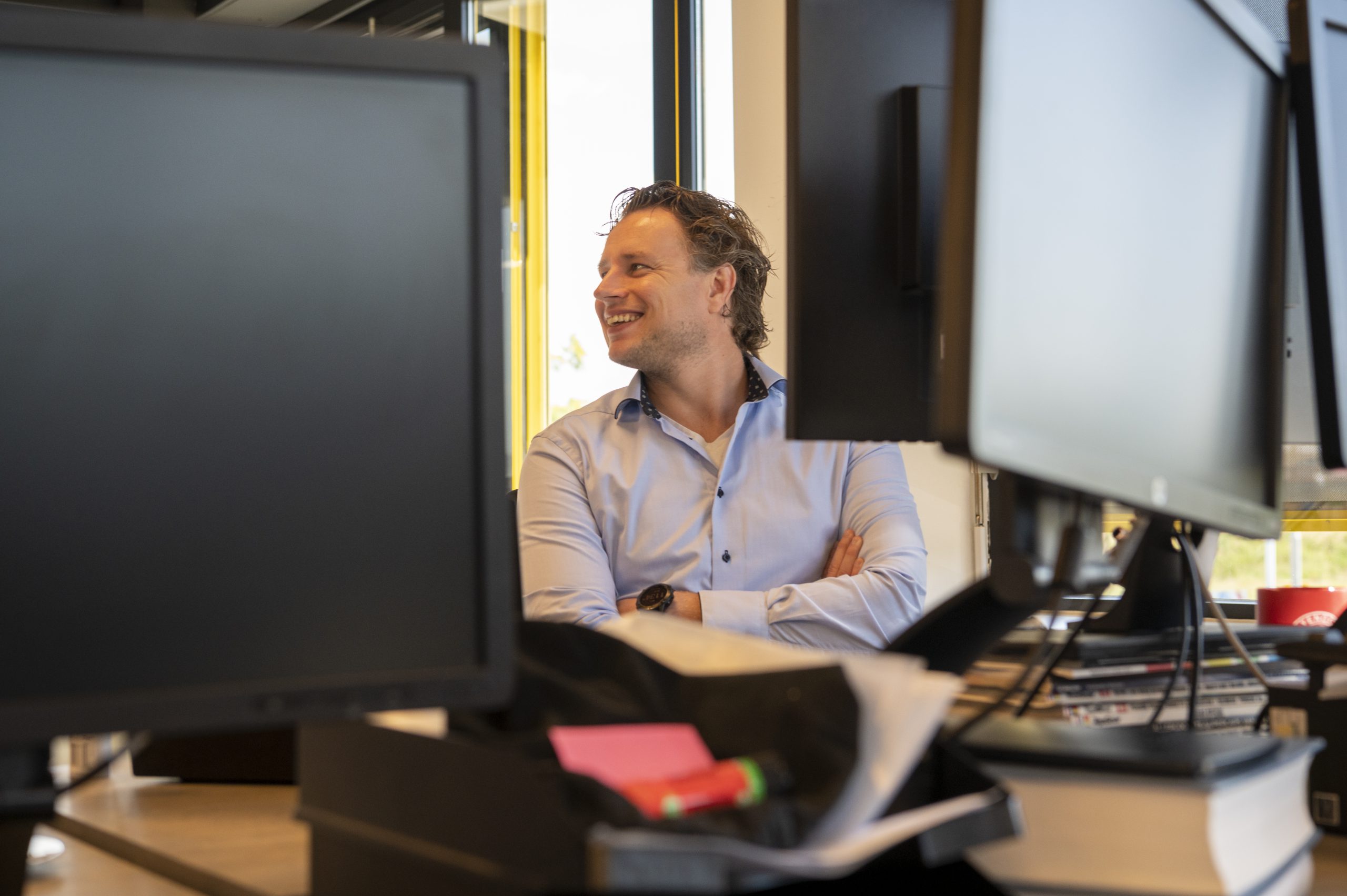Een man zit achter twee monitoren in een kantoor en werkt aan online marketing.